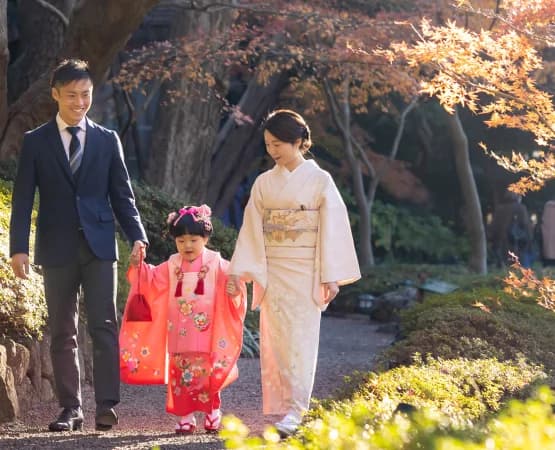 秋の紅葉の中、七五三を祝う家族